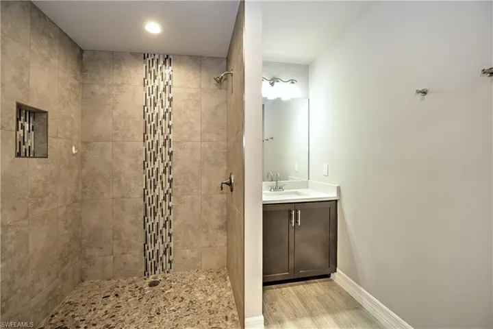 Bathroom featuring a tile shower, hardwood / wood-style floors, and vanity