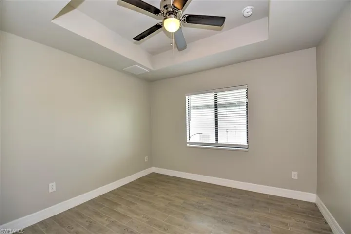 Empty room with ceiling fan, a raised ceiling, and hardwood / wood-style floors