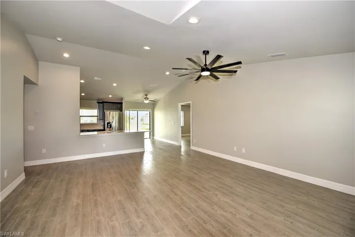 Unfurnished living room with vaulted ceiling, hardwood / wood-style flooring, and ceiling fan
