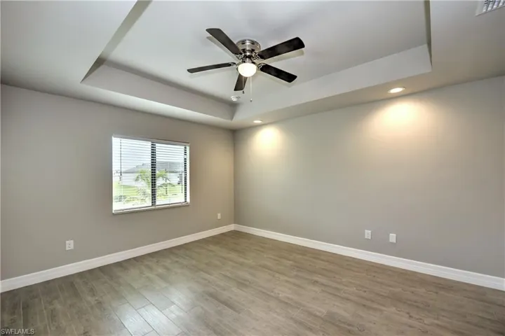 Spare room featuring ceiling fan, hardwood / wood-style flooring, and a tray ceiling