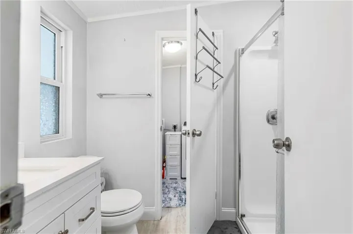 Full bathroom featuring a shower stall, vanity, ornamental molding, light wood finished floors, and a textured ceiling