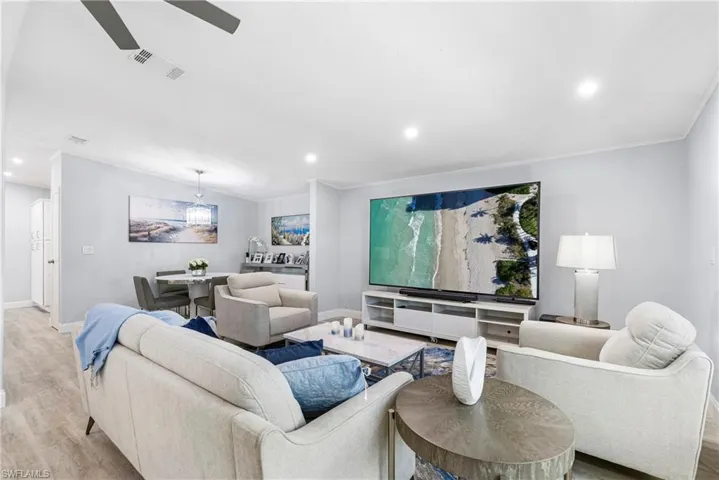 Living area featuring wood finished floors, recessed lighting, a ceiling fan, and ornamental molding