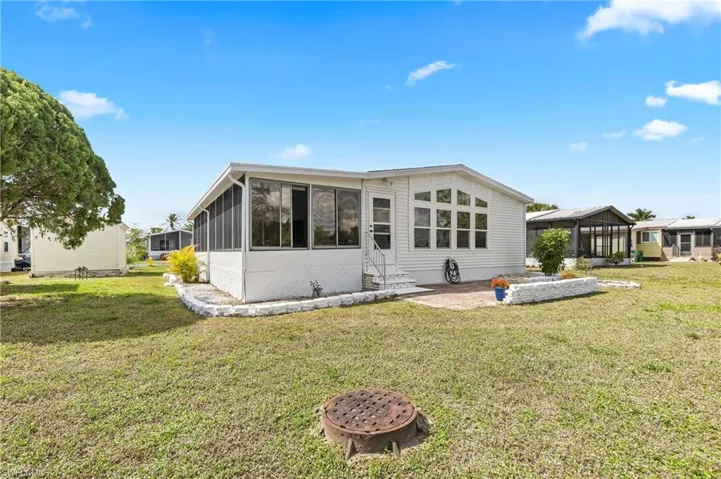 Rear view of house featuring a sunroom, a yard, and a patio area