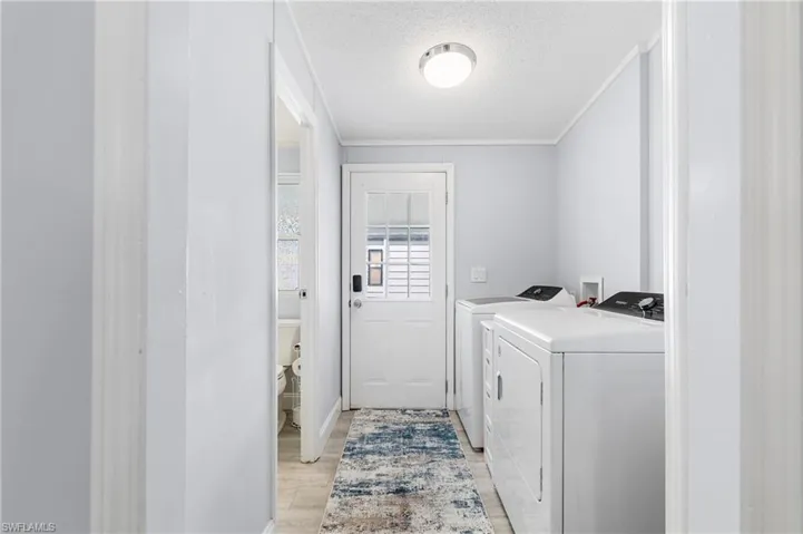 Laundry room featuring a textured ceiling, light wood finished floors, and washing machine and dryer