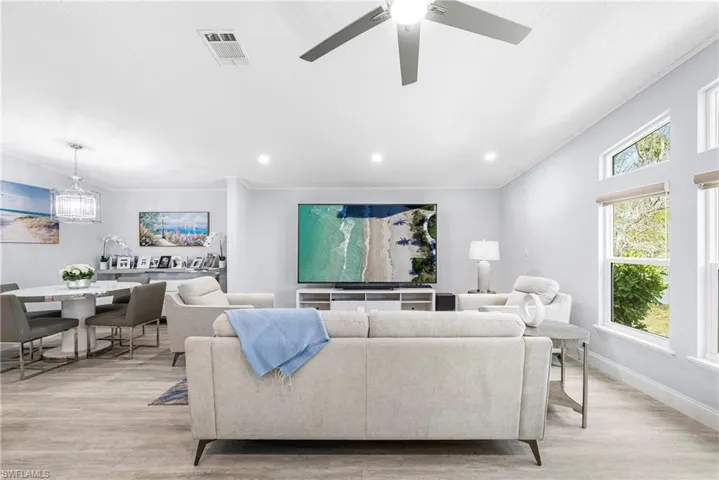 Living room with light wood-style flooring, a ceiling fan, and suspended lighting