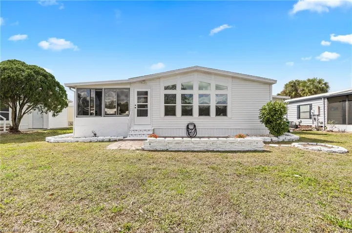 Rear view of property featuring a sunroom, a lawn, and entry steps