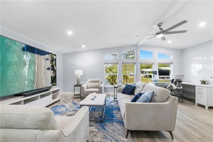 Living area featuring an office area, wood finished floors, ceiling fan, and vaulted ceiling with beams