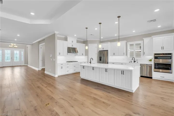 Kitchen featuring stainless steel appliances, pendant lighting, light wood-type flooring, and a center island