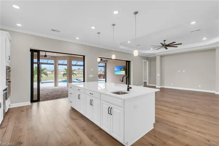 Kitchen with white cabinets, sink, a kitchen island with sink, and light wood-type flooring