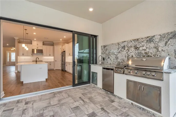 Kitchen featuring stainless steel refrigerator, kitchen peninsula, white cabinets, pendant lighting, and high end fridge