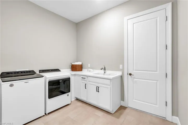 Washroom with independent washer and dryer, cabinets, and sink