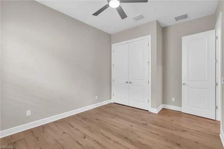 Unfurnished bedroom with light wood-type flooring, ceiling fan, and a closet