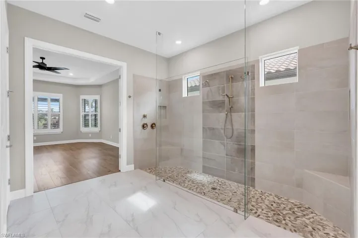 Bathroom featuring a tile shower, a wealth of natural light, hardwood / wood-style flooring, and ceiling fan