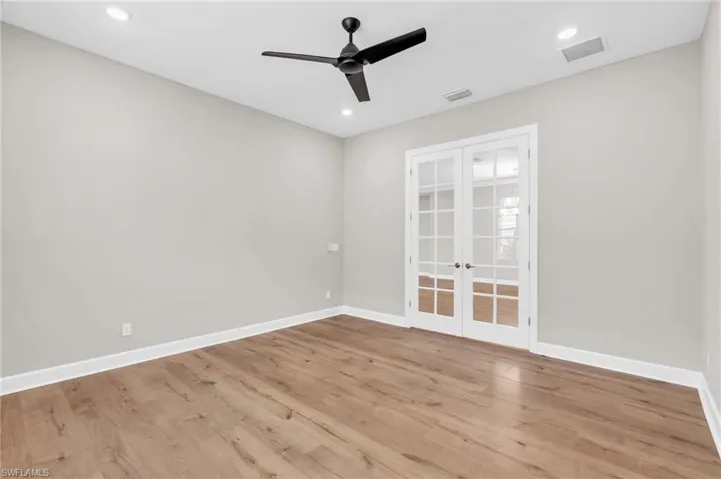 Empty room featuring ceiling fan, light wood-type flooring, and french doors