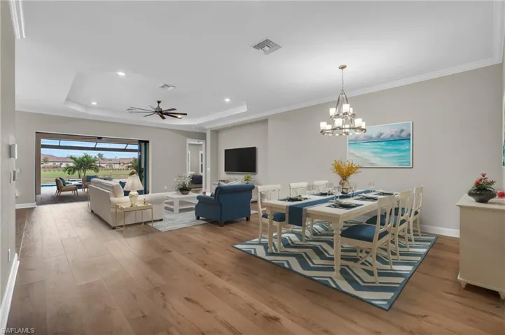 Dining space featuring light hardwood / wood-style flooring, crown molding, and a tray ceiling