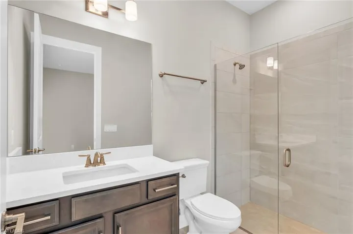 Bathroom featuring vanity, tile patterned floors, toilet, and a shower with door