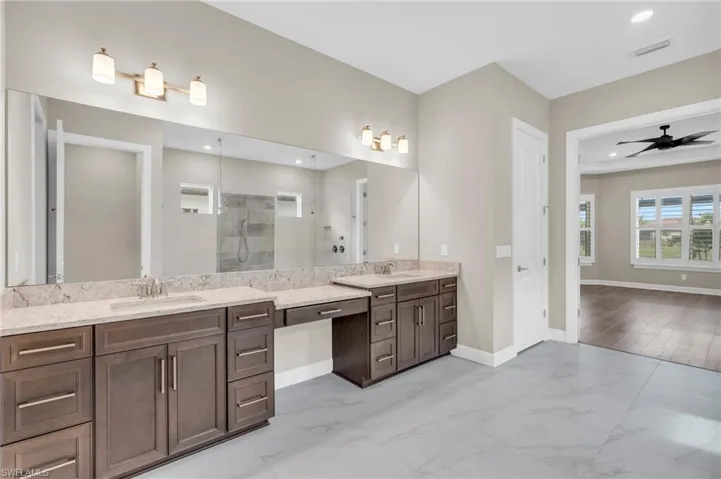 Bathroom featuring ceiling fan, vanity, wood-type flooring, and tiled shower