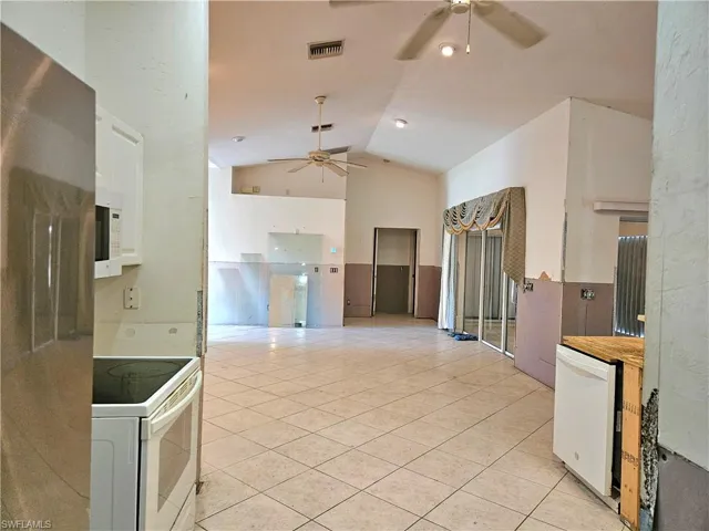 Kitchen featuring white cabinets, light tile patterned flooring, white appliances, and high vaulted ceiling