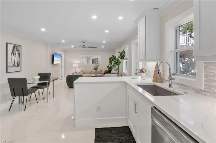 Kitchen with a peninsula, white cabinets, dishwasher, light stone countertops, and recessed lighting