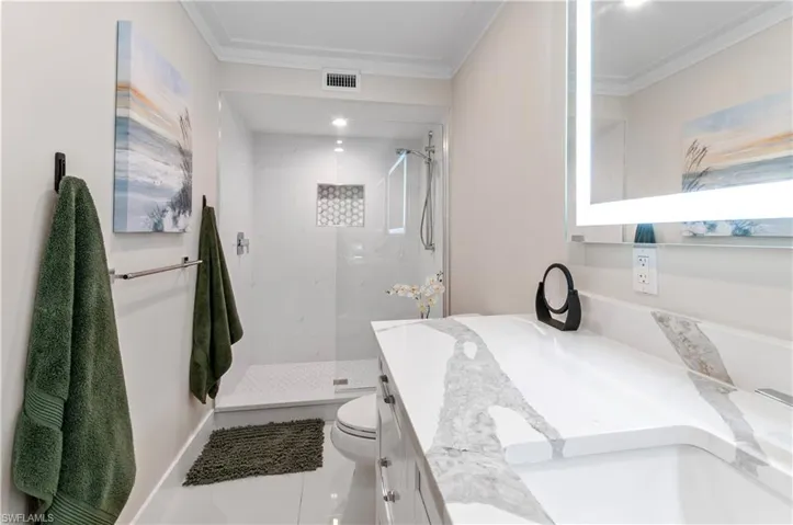 Full bathroom with vanity, a marble finish shower, and ornamental molding