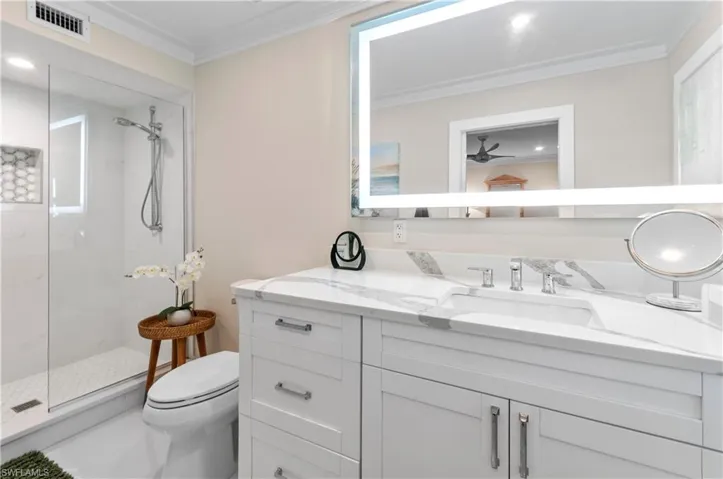 Bathroom featuring vanity, a walk in shower, ornamental molding, and recessed lighting