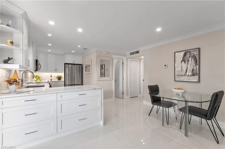 Kitchen with open shelves, ornamental molding, stainless steel appliances, light stone countertops, and white cabinetry