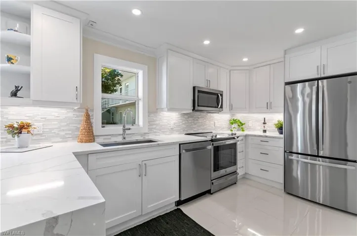 Kitchen featuring stainless steel appliances, white cabinetry, light stone countertops, open shelves, and crown molding