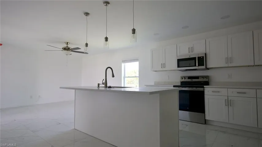 Kitchen with light countertops, marble finish floor, a kitchen island with sink, appliances with stainless steel finishes, and a sink