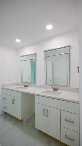 Full bath with marble finish floor, a sink, double vanity, and recessed lighting