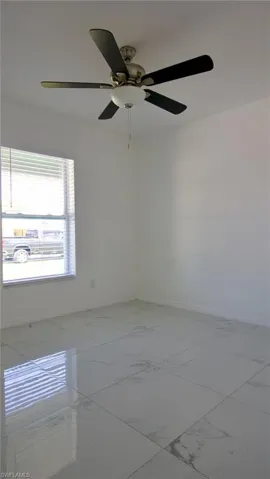 Unfurnished room with a ceiling fan, marble finish floor, and baseboards