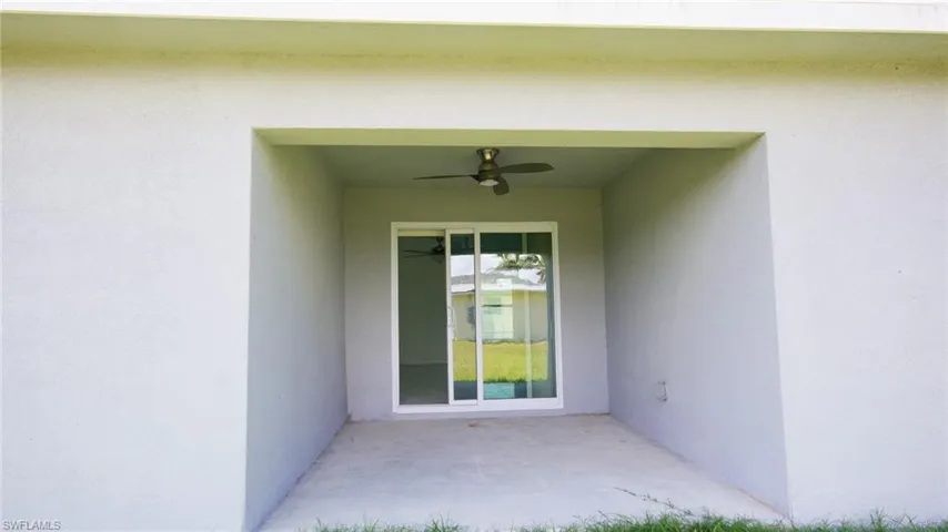 View of exterior entry with stucco siding, a patio area, and a ceiling fan