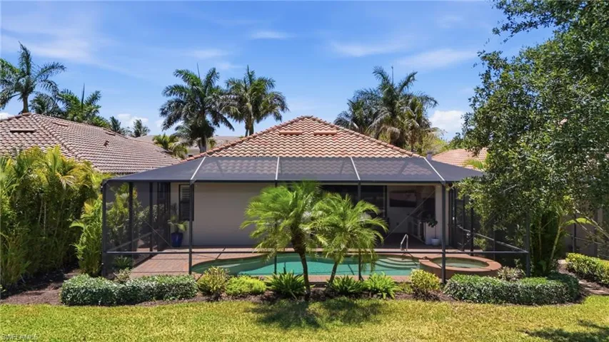 Screened lanai featuring a private pool with an integrated spa, surrounded by mature landscaping and a paver deck