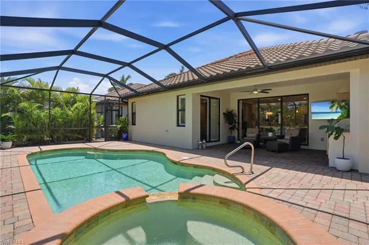 Screened lanai featuring a swimming pool and attached spa with brick coping