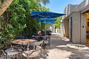 Beach Club Paved patio area featuring lush foliage and multiple blue umbrellas