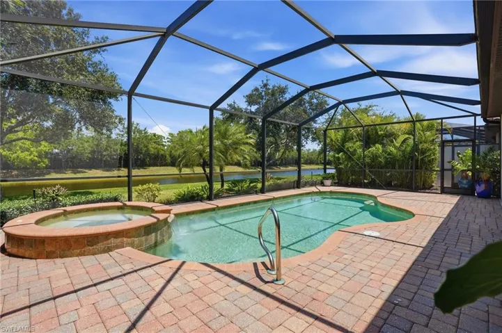Screened lanai featuring a freeform swimming pool and integrated spa with brick-finish surround