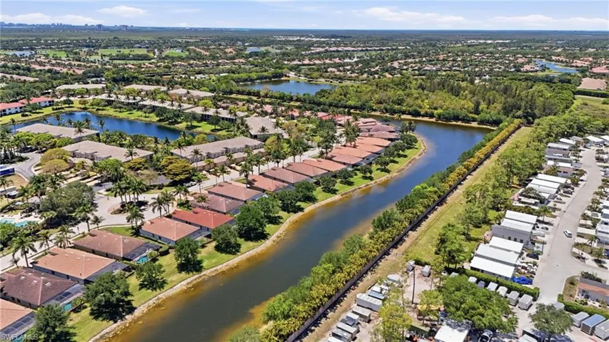 Aerial perspective showcasing a community with numerous residential properties, canals, and natural greenery