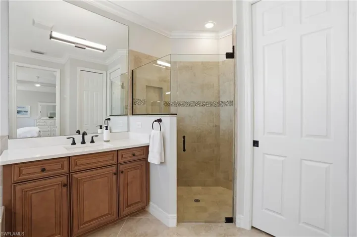 Bathroom featuring a wood-finish vanity with a white countertop, an undermount sink, and a large wall mirror