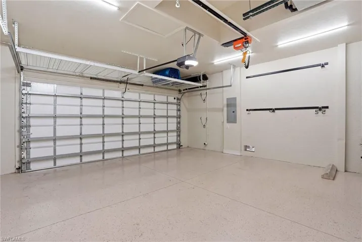 Expansive garage featuring an overhead garage door, a finished floor, overhead storage racks, and built-in wall storage hooks