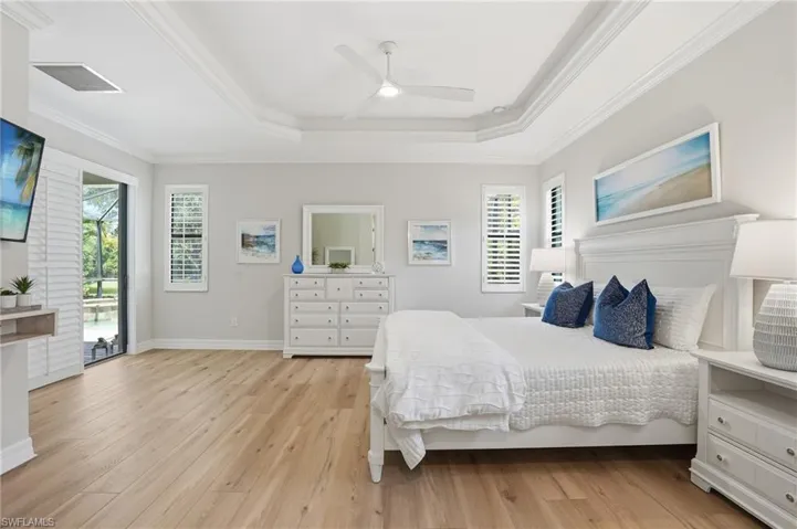 Spacious room featuring wood-finish flooring, a tray ceiling with a fan, and crown molding