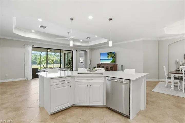 Spacious kitchen island with white cabinetry and a light-toned countertop, featuring an undermount sink and stainless steel dishwasher