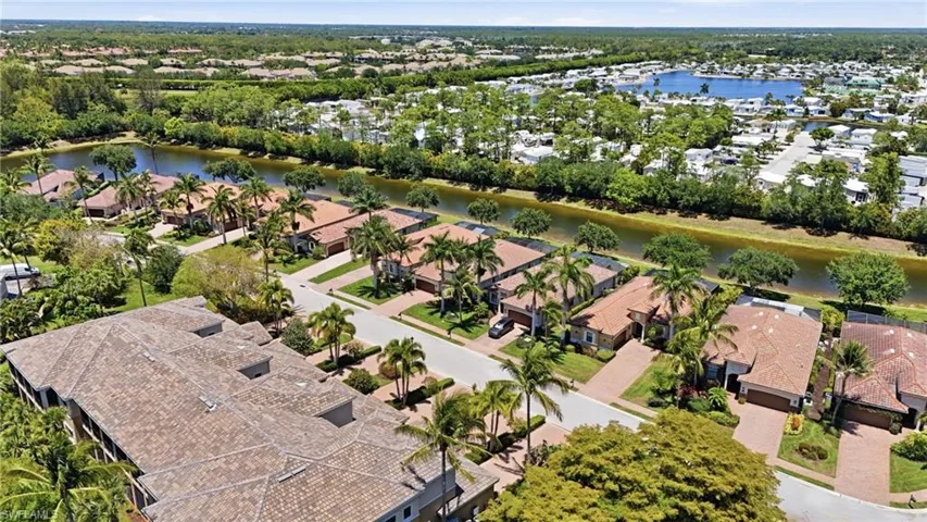 Aerial perspective showcasing a residential community with tiled-roof homes, mature landscaping, and an extensive canal system