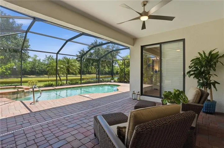 Screened lanai featuring a swimming pool, integrated spa, and brick paver patio