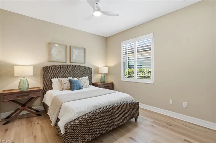 Bedroom featuring light-tone wood-finish flooring, neutral wall paint, and a white ceiling fan