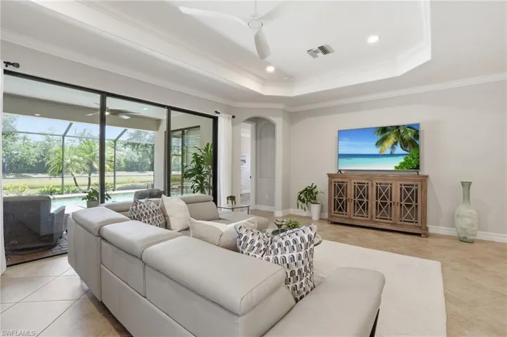 Spacious living area featuring large sliding glass doors opening to a screened lanai with a swimming pool