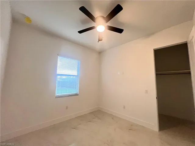 Unfurnished bedroom with a closet, ceiling fan, and a spacious closet