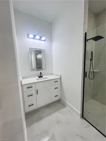 Full bathroom with marble look tile flooring, a marble finish shower, and vanity