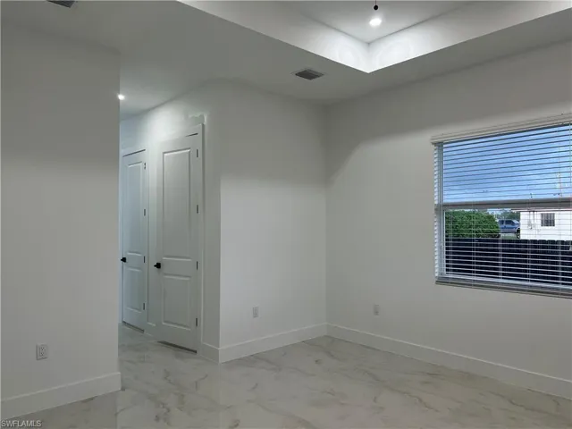 Empty room featuring light marble finish flooring and recessed lighting