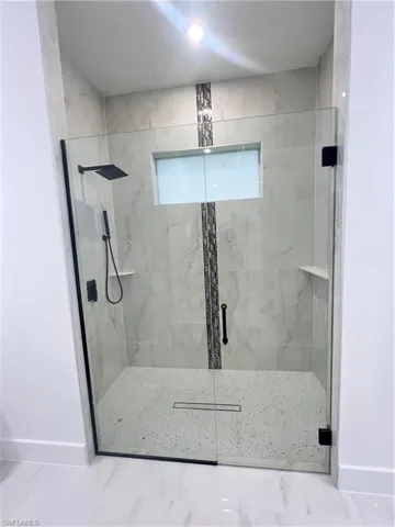 Bathroom featuring a marble finish shower and baseboards