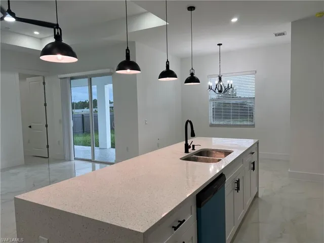 Kitchen featuring dishwashing machine, light marble finish flooring, recessed lighting, plenty of natural light, and white cabinets