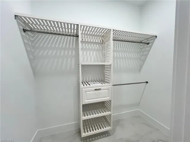 Walk in closet featuring light marble finish floors